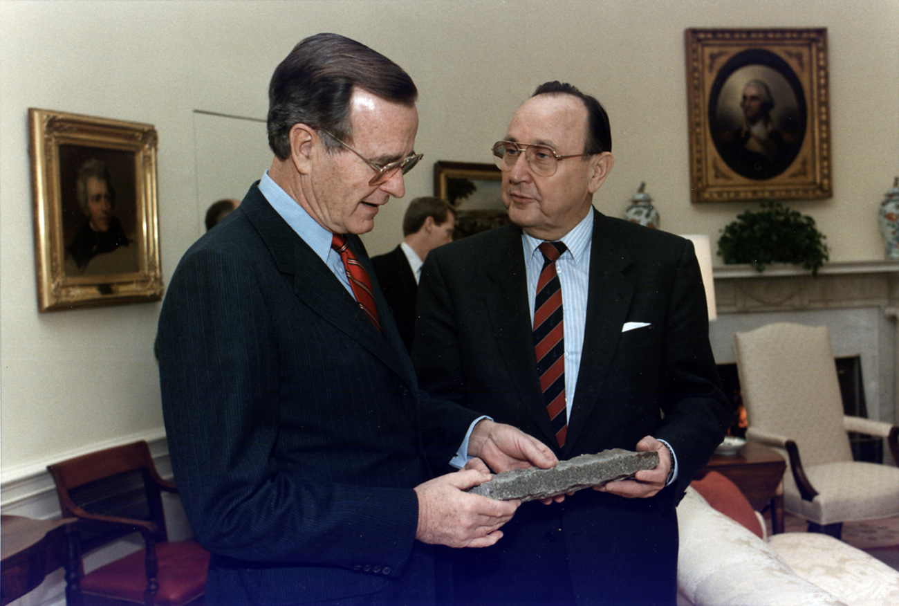 Yhdysvaltain presidentti George Bush ja Länsi-Saksan ulkoministeri Hans-Dietrich Genscher Valkoisessa talossa vuonna 1989. Bush 41:n kädessä pala murtunutta Berliinin muuria. Kuva: Wikimedia Commons